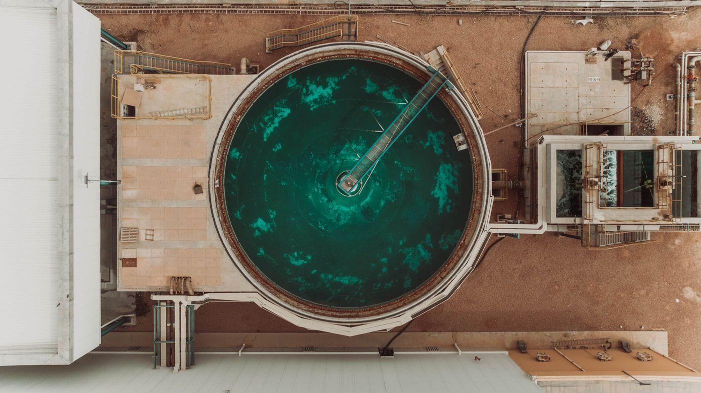 A circular settlement tank at a water treatment and desalination facility, seen from above
