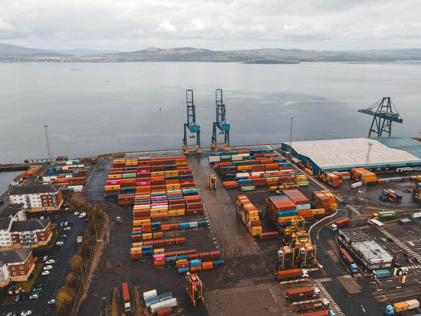 Aerial view of stacked shipping containers and gantry cranes at a busy terminal