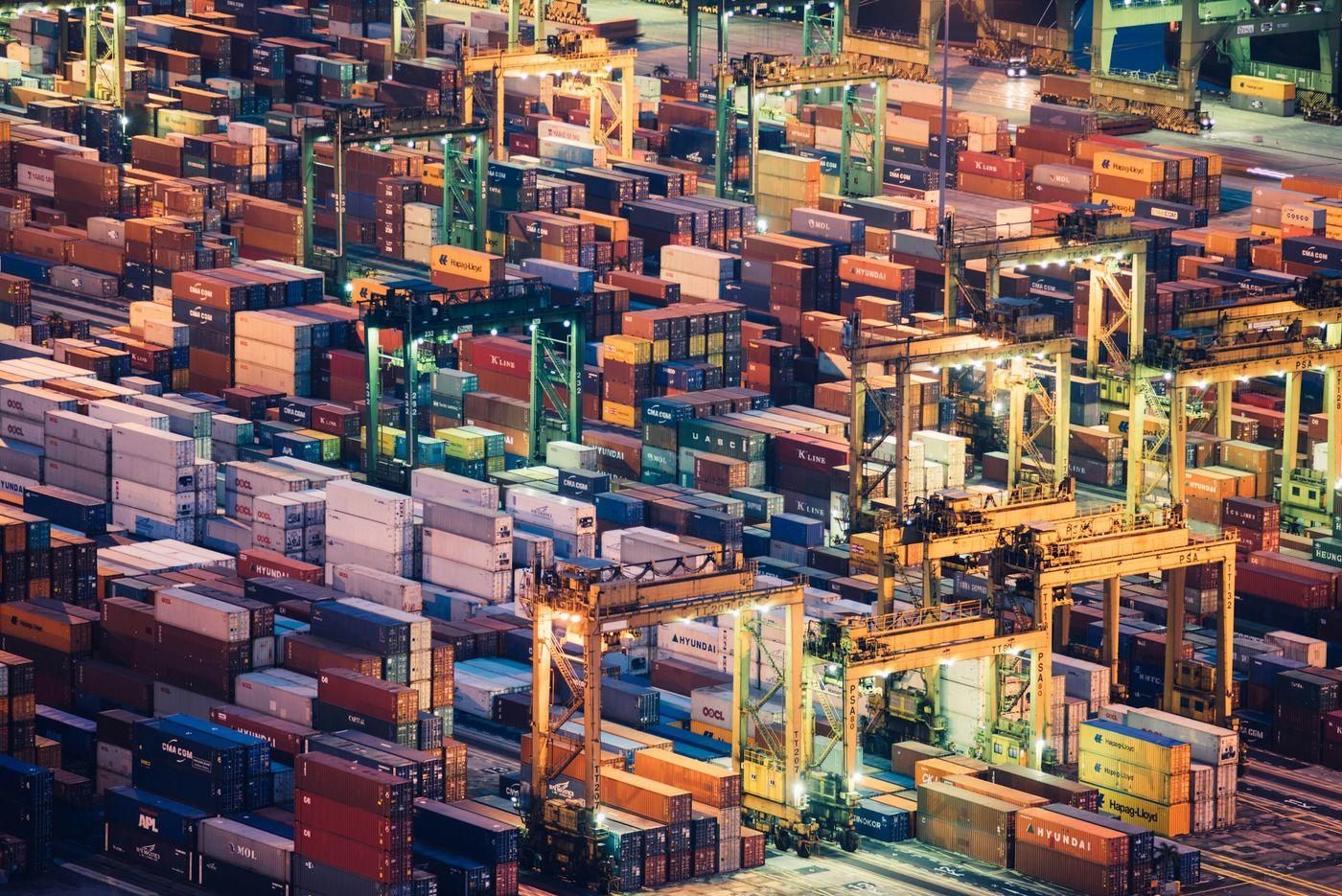 Stacked, multicolored shipping containers at a port terminal seen from directly above